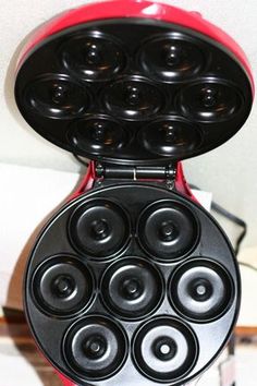 a red and black pancake maker sitting on top of a white counter next to a wall