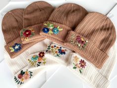 five hats with embroidered flowers on them sitting on top of a white surface, next to each other