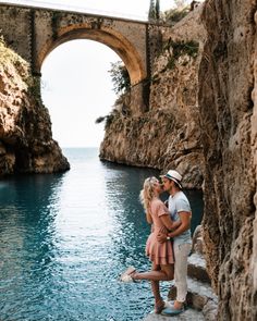 a man and woman standing next to each other near the water