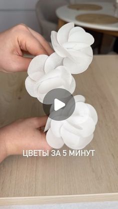 a person is placing white flowers on top of a wooden table