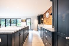 a large kitchen with marble counter tops and black cabinets, along with a clock mounted on the wall