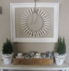 a white table topped with potted plants next to a wall hanging on the wall