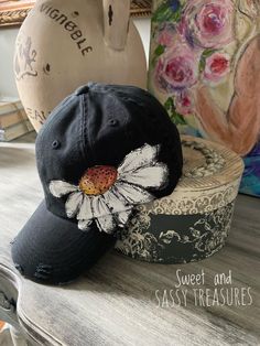 a black hat with a white flower on it sitting on top of a wooden table