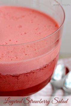 a close up of a drink in a glass on a table with spoons next to it