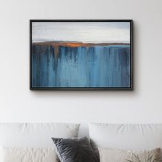 a painting hanging on the wall above a bed in a room with white walls and pillows