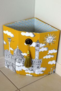 a yellow and white storage box with a tassel hanging from it's side