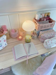 an open notebook sitting on top of a wooden desk next to a lamp and other items