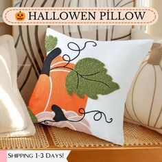 an orange pumpkin pillow sitting on top of a chair next to a white pillow with green leaves