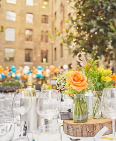 the table is set with wine glasses and flowers in vases on top of it