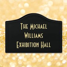 the michael williams exhibition hall sign in front of gold boket background with lights