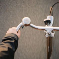 a person riding a bike down a street with their hand on the handlebars