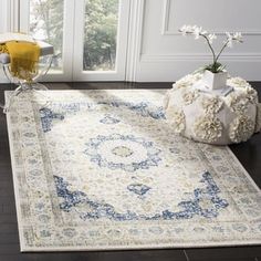 a white rug with blue and yellow flowers on the floor in front of a window