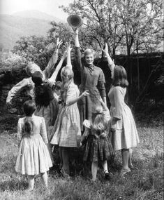 an old black and white photo of children reaching up for a frisbee