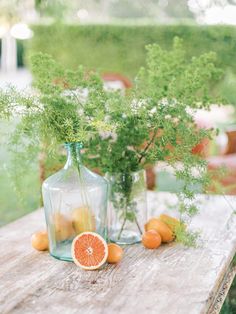 an orange sitting on top of a wooden table next to vases filled with plants