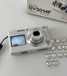 a white camera sitting on top of a table next to some jewels and a box