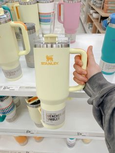 a person is holding a coffee mug in front of some cups on the store shelf