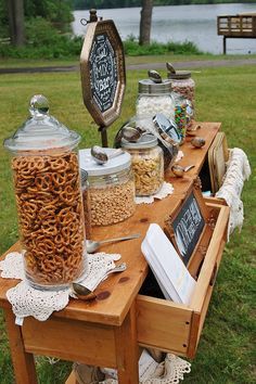 the table is full of food and drinks for an outdoor party or gathering in the park