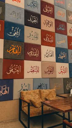 two chairs and a table in front of a wall with many arabic writing on it