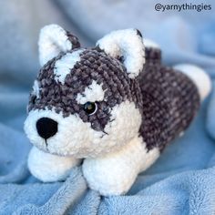 a small stuffed dog laying on top of a blue blanket with white and black stripes