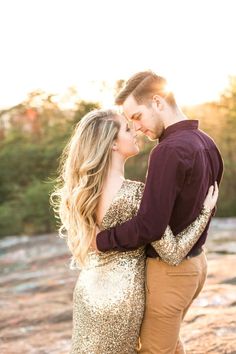 a man and woman standing next to each other on top of a rock covered ground