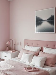 a bedroom with pink walls and white bedding in the corner, along with a painting on the wall