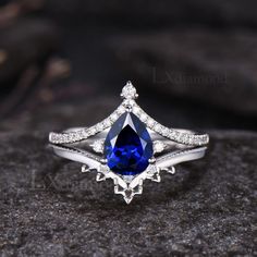 a blue and white diamond ring sitting on top of a rock