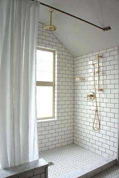 a bathroom with white tile and gold fixtures