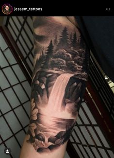 a man's arm with a waterfall and flowers on it