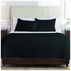 a bed with black sheets and pillows on it