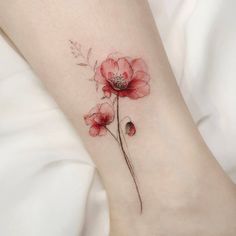 a red flower tattoo on the left side of the leg, with leaves and buds