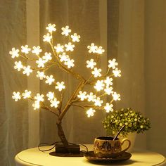 a potted plant sitting on top of a table next to a light up tree