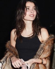 a woman in a black tank top and fur coat