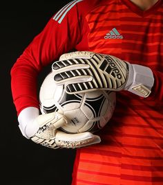 a soccer player is holding a ball in his hands and posing for the camera on a black background