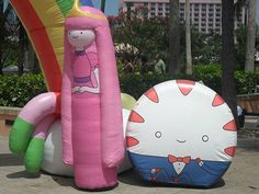 two inflatable toys sitting on the ground next to each other near palm trees