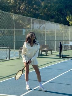 a woman standing on a tennis court holding a racquet in one hand and looking up at the sky