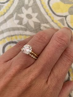 a person's hand with a diamond ring on their finger and the other hand holding an engagement ring