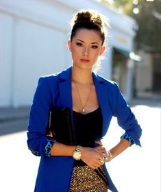 a woman standing in the street wearing a blue coat and leopard print skirt with her hands on her hips