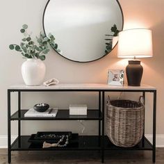 a black and white console table with a round mirror on the wall next to it