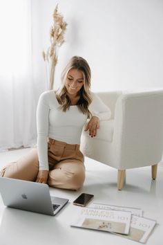 a woman sitting on the floor next to a laptop