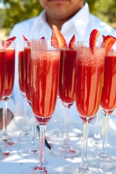 four glasses filled with pink liquid and strawberries