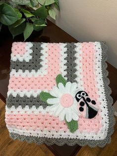 a crocheted blanket sitting on top of a table next to a potted plant