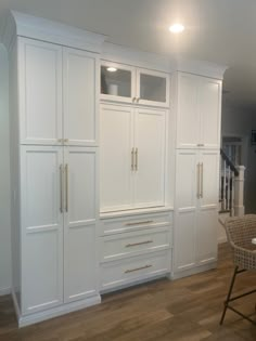 an empty kitchen with white cabinets and chairs in the center, along with a dining room table