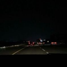 some cars driving down the highway at night