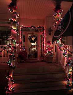 christmas lights decorate the front porch of a house with wreaths and garlands on it