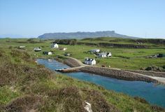 a small village on the side of a grassy hill with water running down it's sides