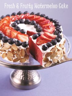 a cake with fruit and nuts is on a silver platter, ready to be eaten