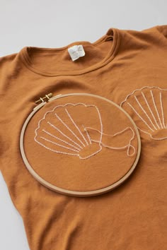 an orange t - shirt with white embroidery on the front, and a shell in the back