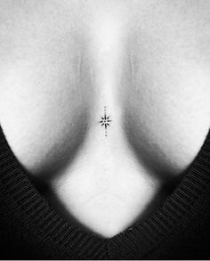 a black and white photo of a woman's breast with a small star tattoo on it