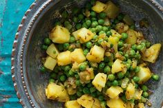 a bowl filled with peas and potatoes on top of a table