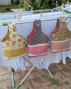 three aprons are hanging on a clothes line with two ironing boards in front of them